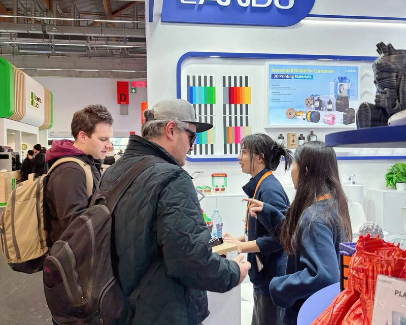 Busy LANDU exhibition booth with team members discussing 3D printing solutions with clients.