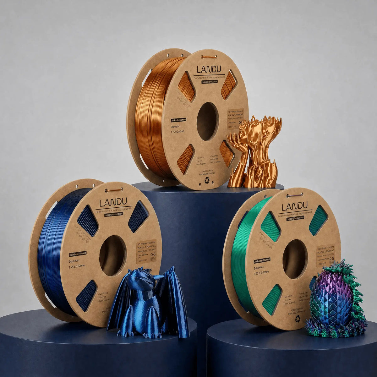 LANDU Aesthetics filament collection featuring glossy Silk PLA spools in copper, blue, and dual-color, displayed alongside highly detailed 3D printed artistic dragon models.