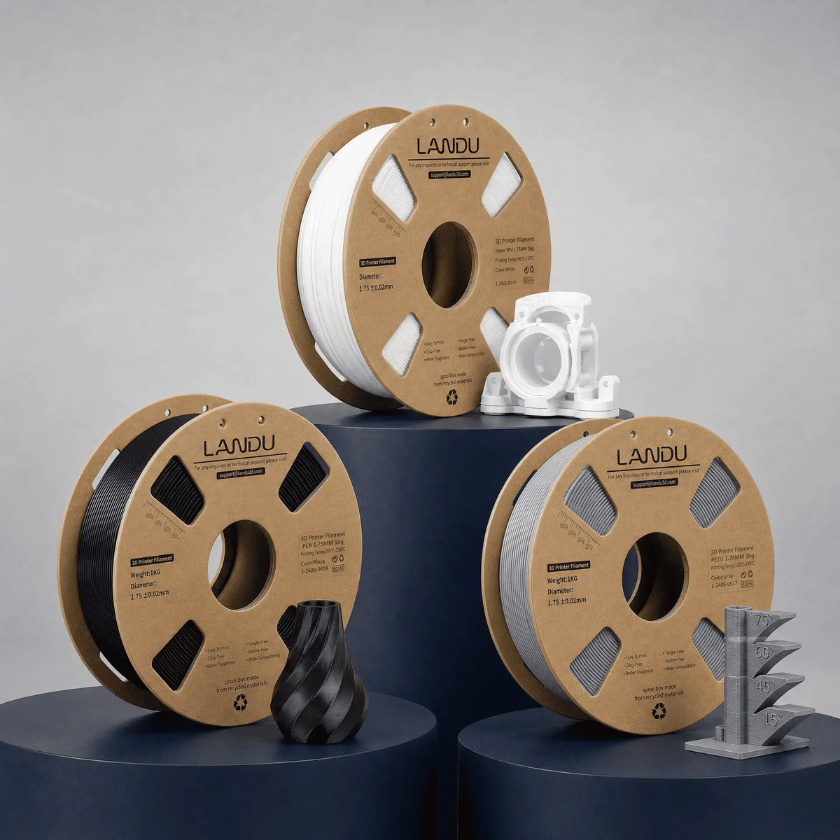 LANDU General 3D printing filament collection showcasing white, black, and gray spools on eco-friendly cardboard, paired with functional parts and 3D printed test models.