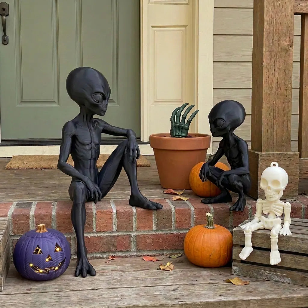 Black alien figures, white skeletons, green skeletal hand and pumpkins at a Halloween-styled front door