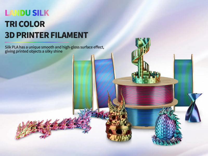 LANDU Silk Tri Color PLA 3D printer filament spools alongside a 3D printed dragon, skull, and castle demonstrating a high gloss silky shine.